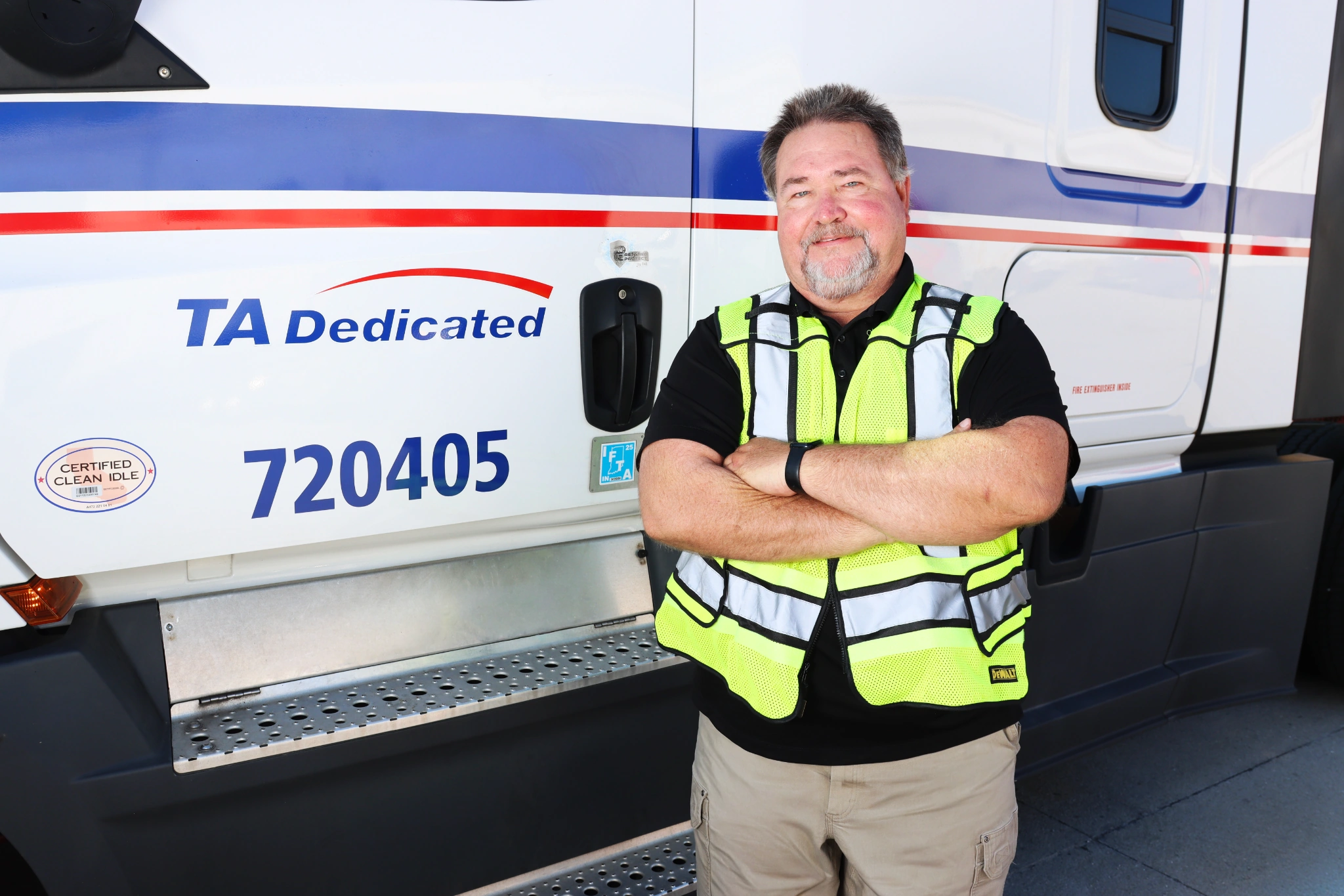Hazmat transportation driver standing in front of dedicated commercial truck