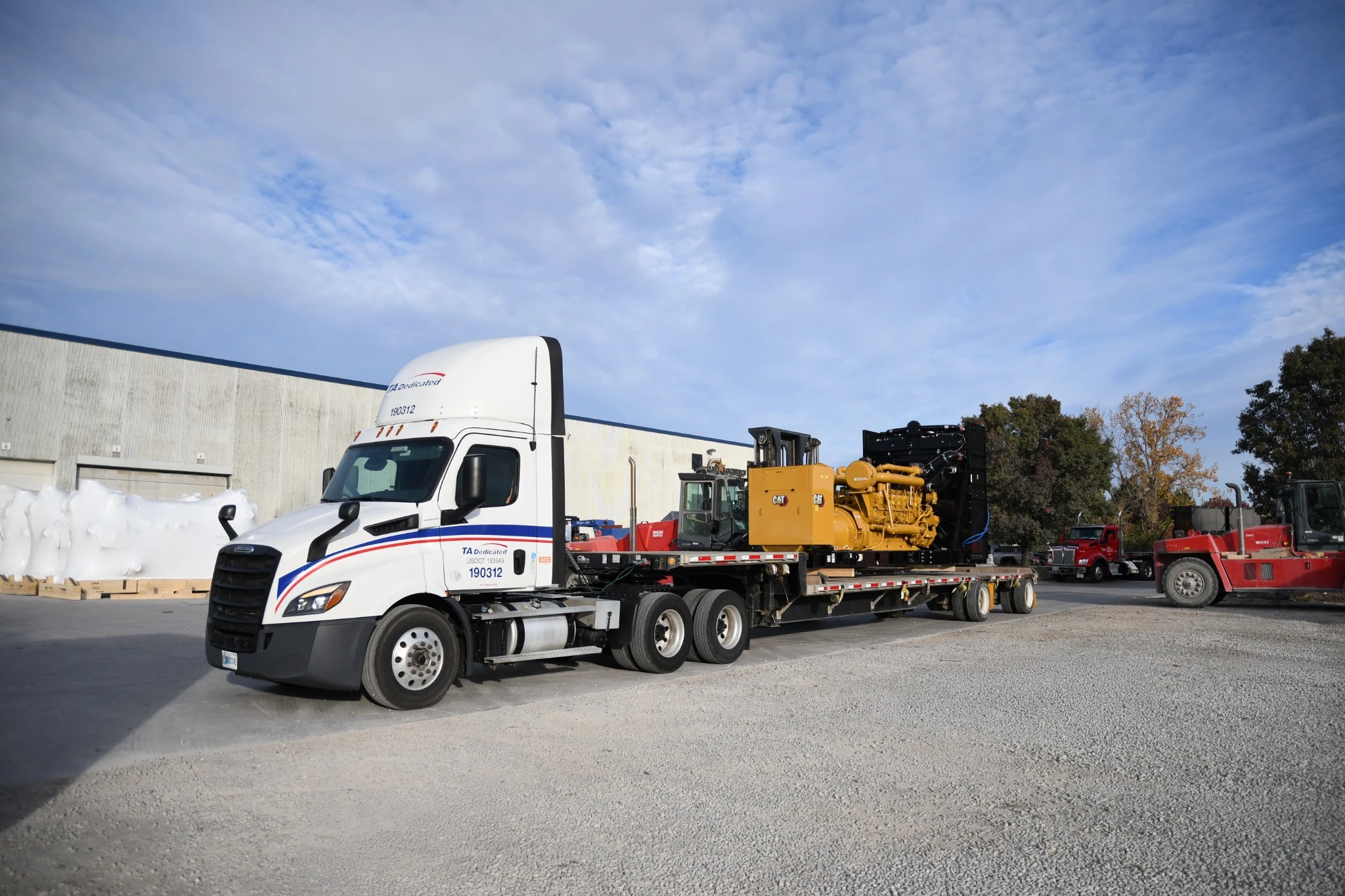 Flatbed semi truck hauling heavy industrial generator equipment for heavy haul shipping and freight services