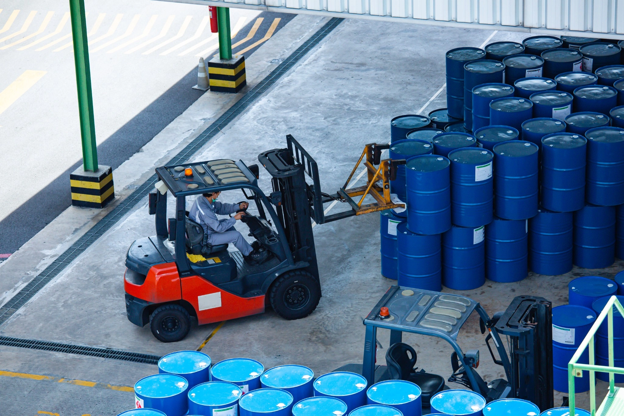 Forklift loading blue chemical barrels in a warehouse for dedicated chemical logistics transportation