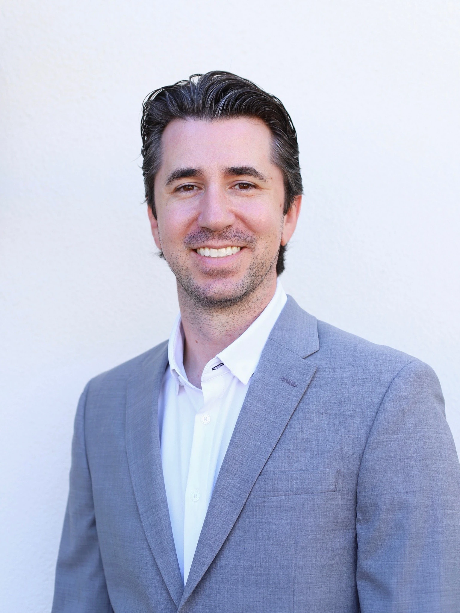 Shawn Miller business headshot smiling in gray blazer against neutral background