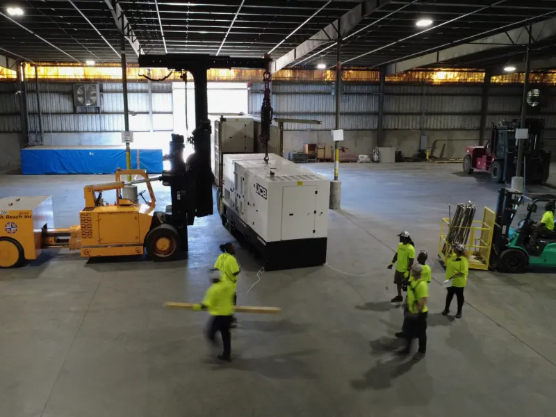 Flatbed truck delivering CAT industrial generator to job site for on-site logistics and equipment delivery services