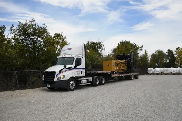 Flatbed truck delivering data center equipment and generator for industrial logistics and infrastructure transport